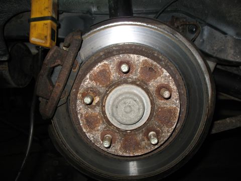 1996 Ford Probe - Rear brake rotor and caliper assembly showing signs of rust and wear.