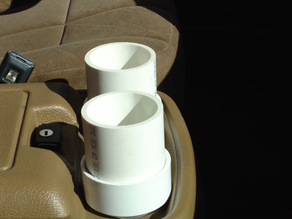 White PVC pipe cup holders mounted in tan vehicle center console interior