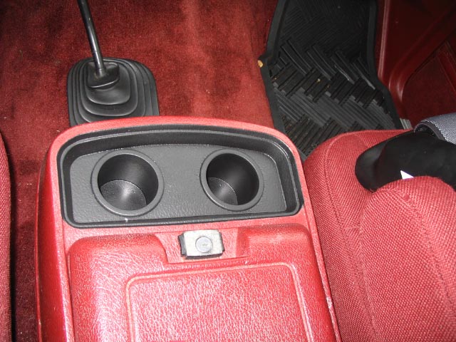 Black dual cupholders on red center console with red carpet interior