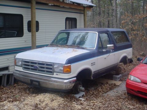 1988 Ford Bronco - This two-tone blue and white 1988 Ford Bronco is missing its wheels and appears to be parked next to a recreational vehicle.