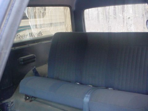 1988 Ford Bronco - The interior of a vehicle shows a rear seat and a "Four Winds" sticker visible through the back window.