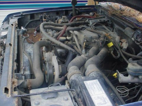 1988 Ford Bronco - The engine bay of a vehicle is shown, with various hoses and mechanical parts visible. The hood appears to be open.