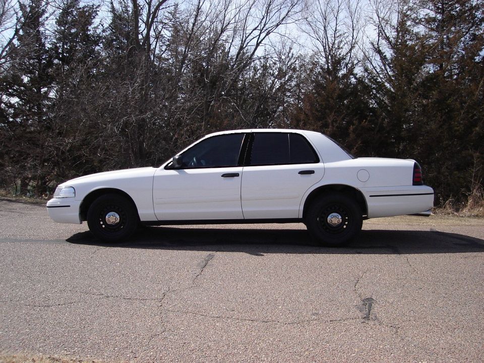 White 2000 Ford Crown Victoria sedan parked on asphalt road, side view