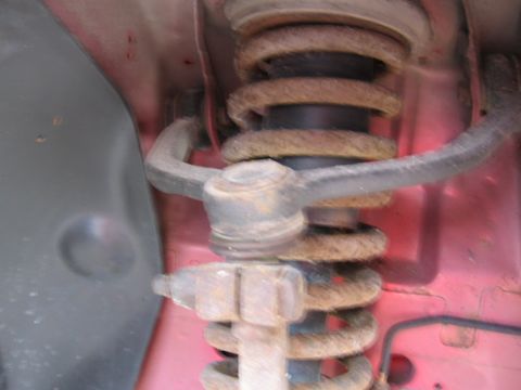 1995 Ford Thunderbird - Close-up of a rusty suspension strut and coil spring assembly, likely from a vehicle's wheel well.