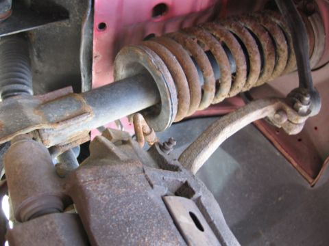 1995 Ford Thunderbird - Close-up of a corroded vehicle suspension system, showing a brake caliper and shock absorber.