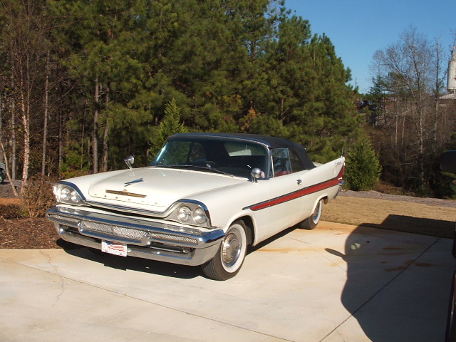 White convertible with red side trim and black top parked on concrete
