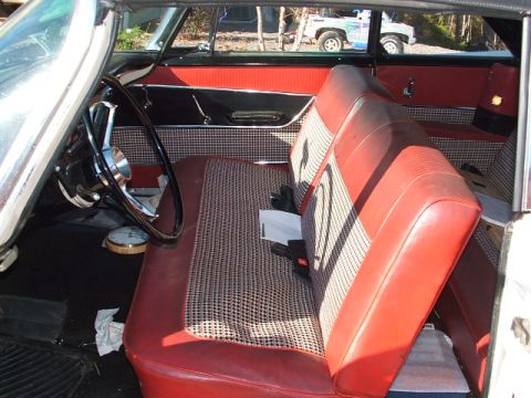 1966 Ford Ranchero - The interior of a vintage car features red vinyl seats with a patterned fabric insert and a large steering wheel.