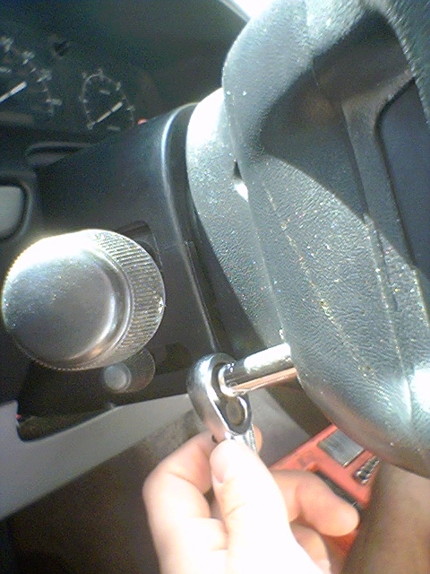 1994 Ford Bronco - Close-up of a hand working on the steering column with a ratchet and socket.