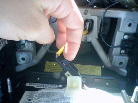 1994 Ford Bronco - A hand disconnects a wiring harness from the steering column clock spring assembly.