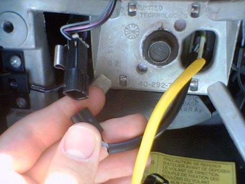 1994 Ford Bronco - A hand disconnects wiring from a steering column component, revealing part numbers and manufacturer information.