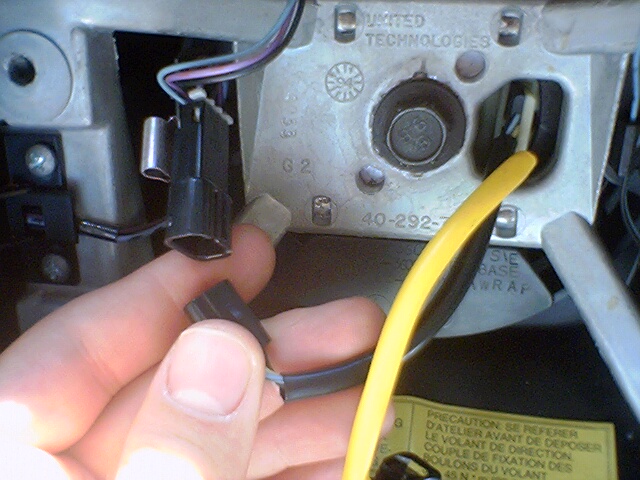 Close-up of steering column wiring with a hand holding a connector. Part number 40-292-7 visible