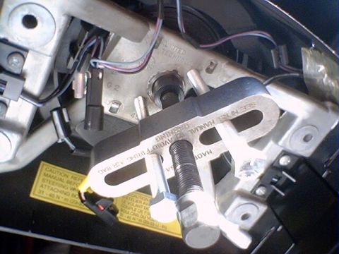 1994 Ford Bronco - A specialized tool is attached to the steering column, with a caution sticker warning about airbag firing.