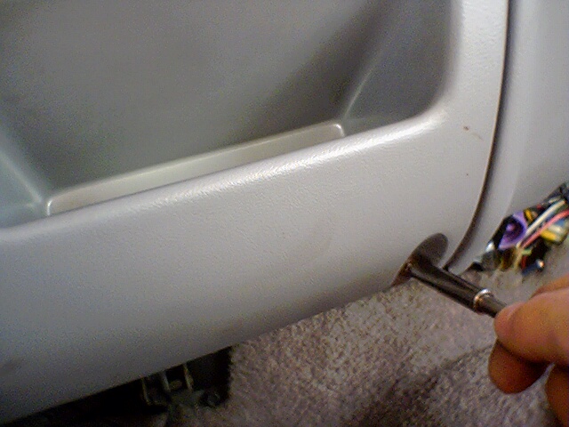 Interior panel with exposed wiring and a tool. Gray plastic trim is visible