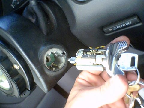 1994 Ford Bronco - A hand holds a removed ignition cylinder and key, with the steering column of a 1994 Ford Bronco visible.