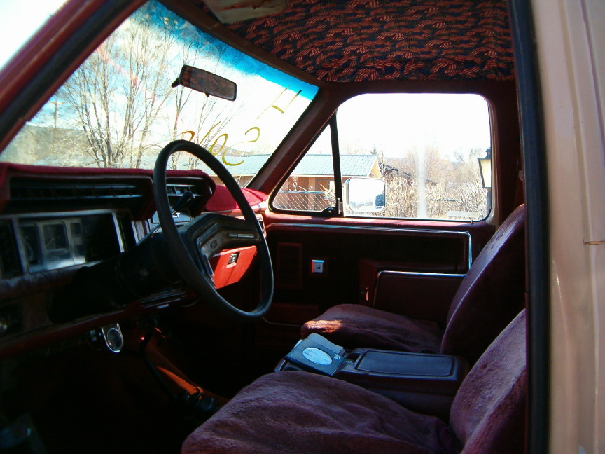 Interior shot of a vehicle, showing the steering wheel, dashboard, and seats. The headliner has a patterned fabric