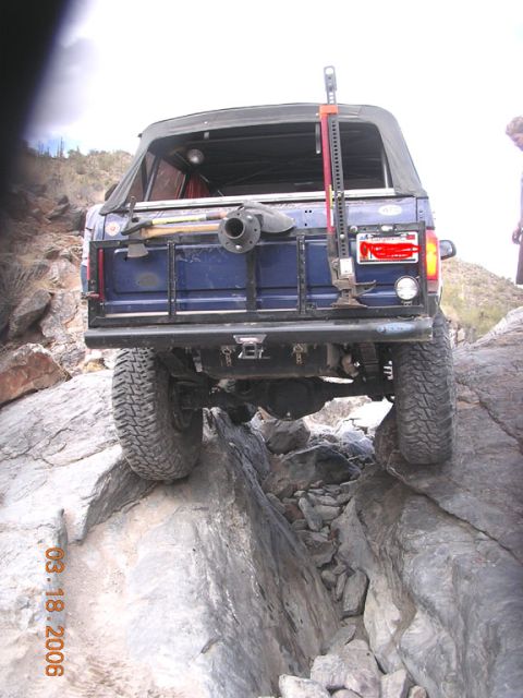 1994 Ford Bronco - This 1994 Ford Bronco is navigating a difficult rocky trail, showing its rear end and off-road modifications.