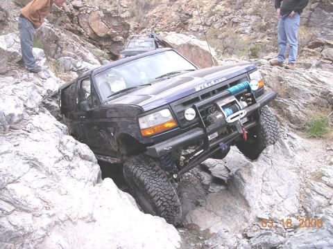 1994 Ford Bronco - This 1994 Ford Bronco is tackling a challenging off-road course with a second vehicle visible in the background.