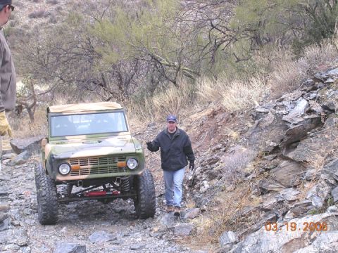 1994 Ford Bronco - Ford Bronco navigates a challenging rocky terrain with a person standing nearby.