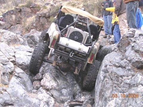 1994 Ford Bronco - A modified off-road vehicle navigates a challenging rocky trail with spectators watching.