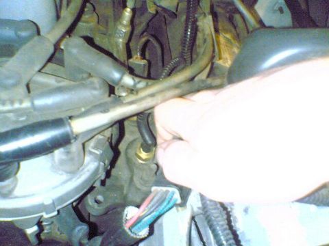 1996 Ford Bronco - Engine bay detail with a hand interacting with a sensor. Wires and hoses are prominent.