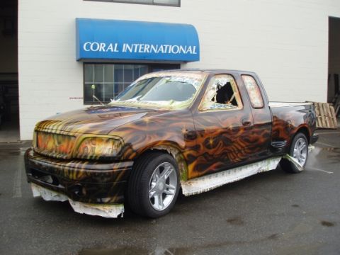 1985 Ford Bronco II - This truck has custom flame paint and broken windows, with paper protecting the front bumper.