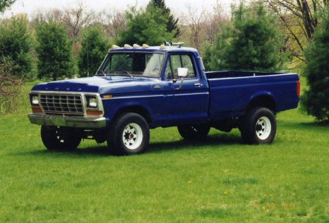 1994 Ford Bronco - This blue Ford pickup truck is parked on a grassy lawn with trees in the background.