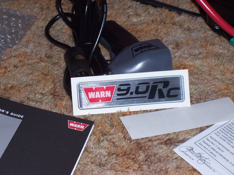 WARN 9.0Rc badge sticker, corded remote and owner's guide booklet on carpet