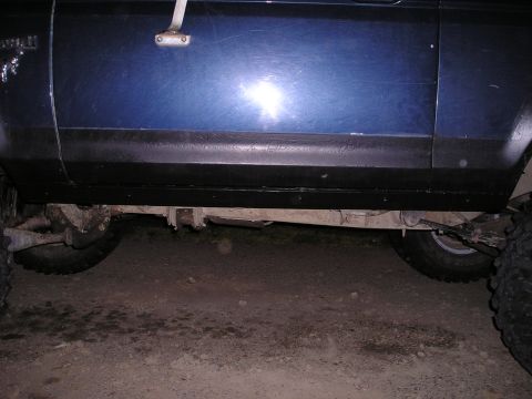 1986 Ford Bronco II - The side panel and undercarriage of a blue 1986 Ford Bronco II are visible, with the 'Bronco II' badge clearly displayed.