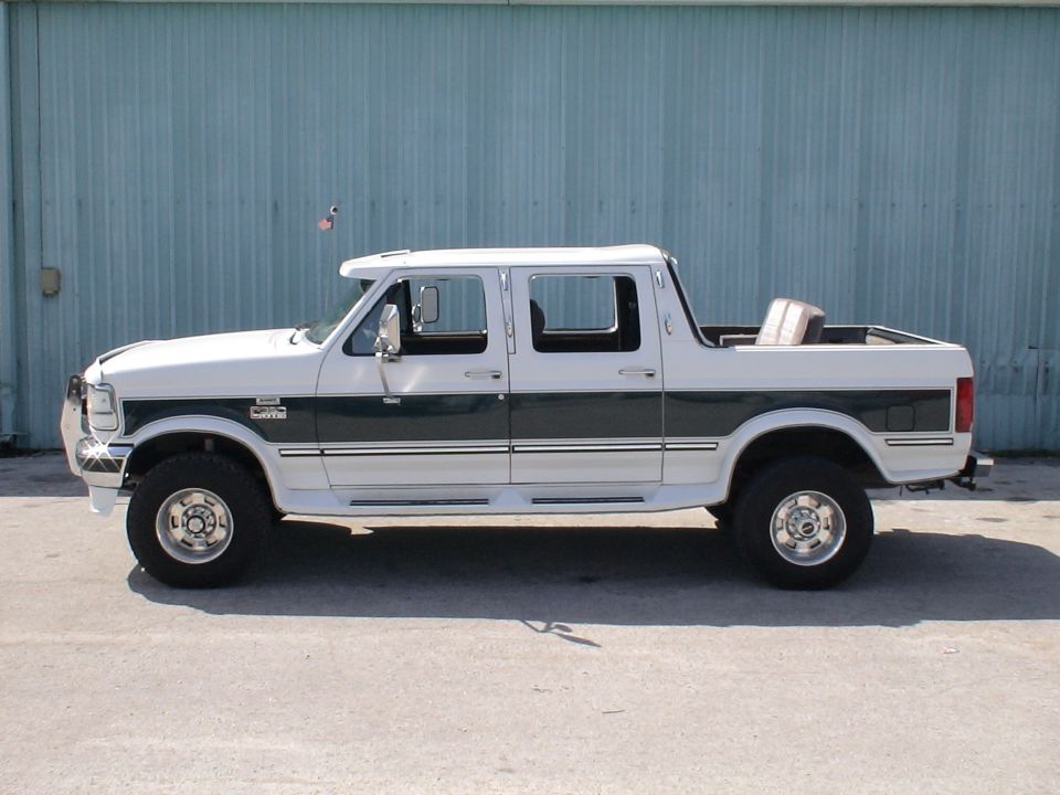 Side view of white and green lifted Ford crew cab pickup truck