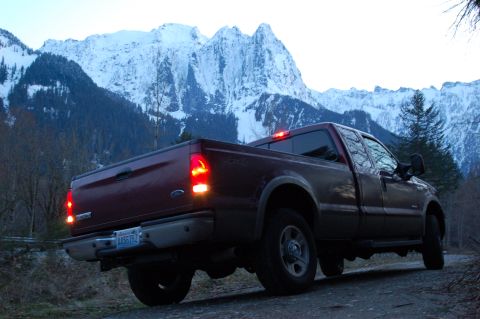 2006 Ford F-250 - Maroon Ford Super Duty pickup truck on a dirt road with snowy mountains behind it.