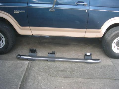 1986 Ford Bronco - Side view of a 1986 Ford Bronco with a running board placed in front of it.