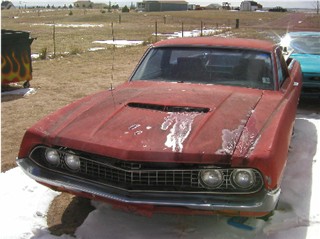 1972 Ford Ranchero - A weathered red 1970 Ford Ranchero sits in a snowy outdoor lot, its paint showing significant wear and tear.