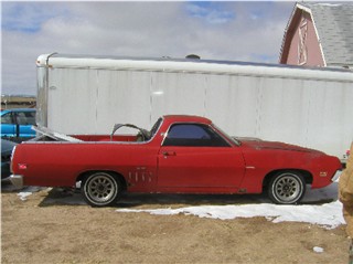 1972 Ford Ranchero - A red 1972 Ford Ranchero pickup truck is seen from the side, parked outdoors.