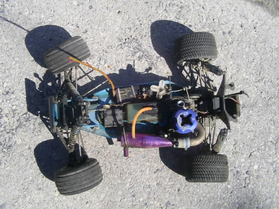 Top-down view of a remote control nitro car with a blue engine and purple exhaust pipe