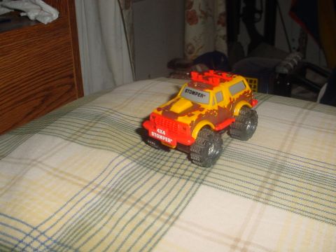 1988 Ford Bronco - A toy monster truck with "4X4 STOMPER" visible on the front bumper is shown on a patterned surface.