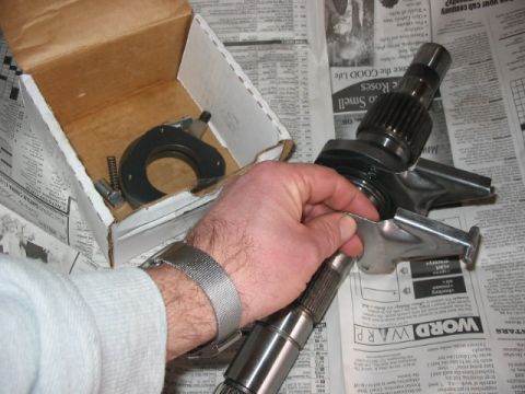 1995 Ford Bronco - A person holds a metal transfer case part, with a box of other components nearby, against a backdrop of newspaper pages.