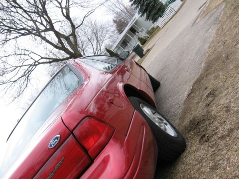1995 Ford Thunderbird - This red Ford Thunderbird is parked on the side of a residential street. The rear of the vehicle is visible, including the taillight and Fo…