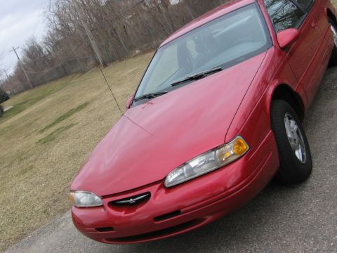 1995 Ford Thunderbird - A red Ford Thunderbird is shown from the front quarter angle, parked outdoors.