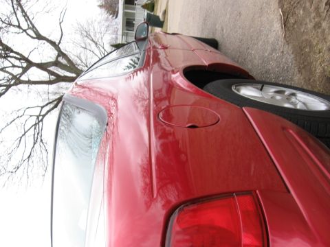 1995 Ford Thunderbird - A red coupe is parked on the side of the road with a tree and house in the background.