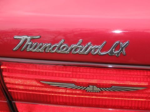 1995 Ford Thunderbird - Close-up of a red car's rear, showing the Thunderbird LX emblem and a detailed taillight design.