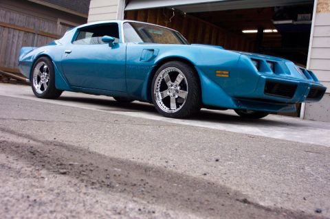 1979 Pontiac Trans Am - This blue Pontiac Firebird is parked outside a garage with the door open. It features aftermarket wheels.