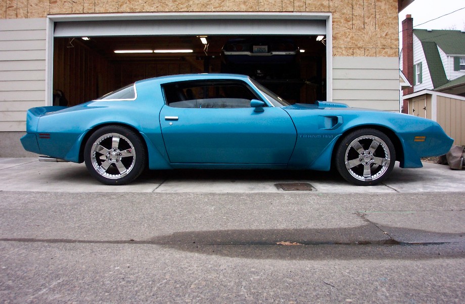 Blue coupe with custom chrome wheels parked in front of an open garage
