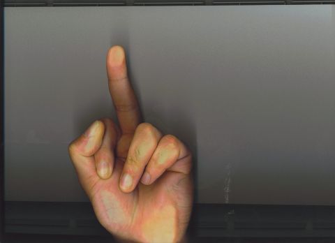 1991 Ford Bronco - A hand is shown giving the middle finger gesture against a plain gray backdrop.