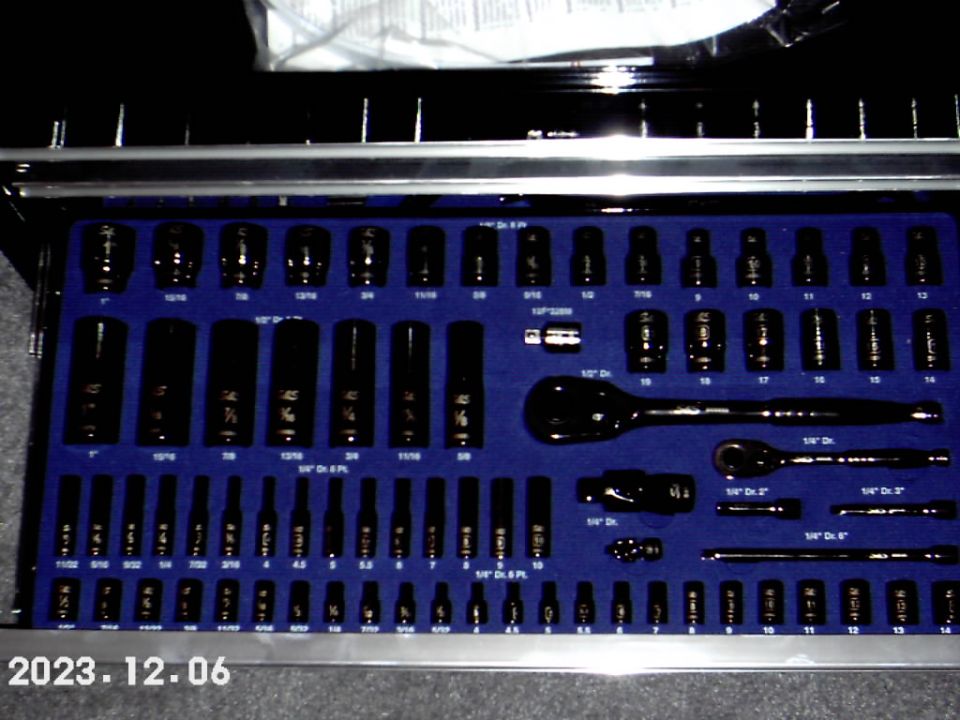 Tool chest drawer filled with black sockets and ratchets on blue foam organizer