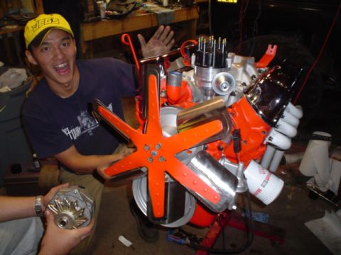 1981 Ford Bronco - A person in a yellow cap poses with a V8 engine, which is partially assembled with an orange fan and chrome details.