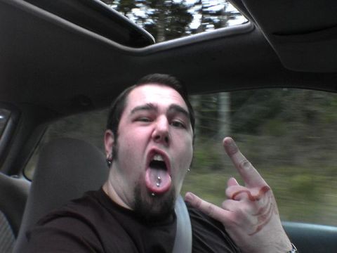 1994 Ford Probe - A man makes a rock-on hand gesture while sticking out his tongue, inside a car.