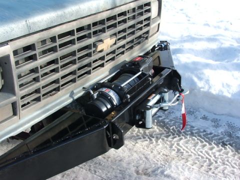 1990 Chevrolet Suburban - A winch is mounted to the front bumper of a truck, with snow on the ground.