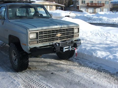 1990 Chevrolet Suburban - Front view of a 1990 Chevrolet Suburban, equipped with a winch mounted on the bumper, in a snowy environment.