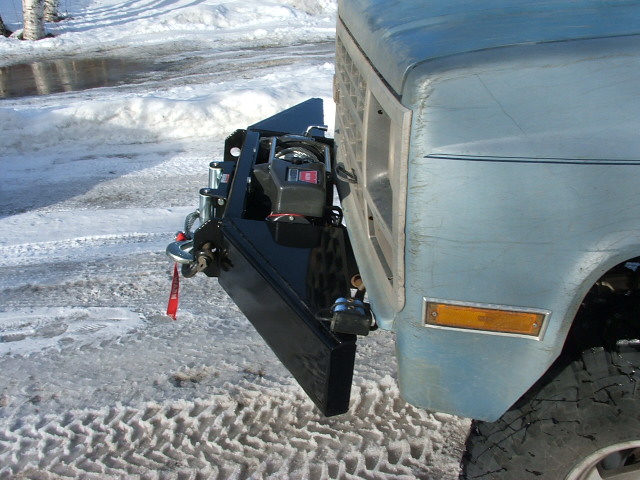 Corner detail of black tube winch bumper with shackle on a light blue square-body Chevy