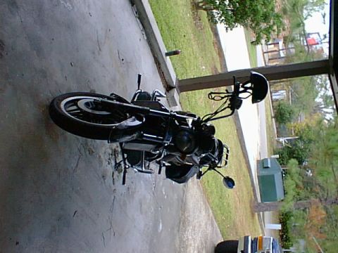 1981 Honda GL11GoldWing - A black motorcycle is parked on a concrete surface, with a helmet attached to the handlebars.